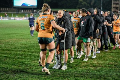 010825 - Australia Women v Wales Women - Alex Callender of Wales on crutches congratulates the Australian team