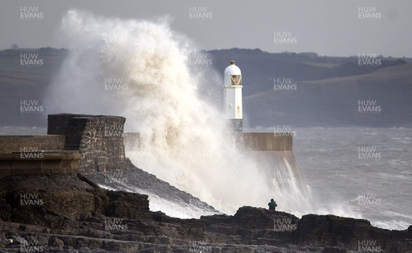 160118 - Picture shows a man walking on the rocks as the windy weather hits the South Wales coast at Porthcawl