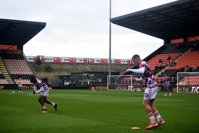 290725 - Barnet v Newport County - Carabao Cup Preliminary Round - Newport players warmup as a train goes past the Hive Stadium