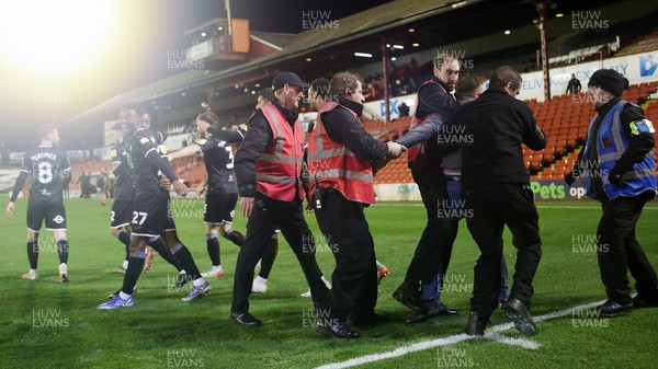 241121 - Barnsley v Swansea City - Sky Bet Championship - Swansea team leave the area where fans encroach onto the pitch after the 1st goal Stewards arrest the fan