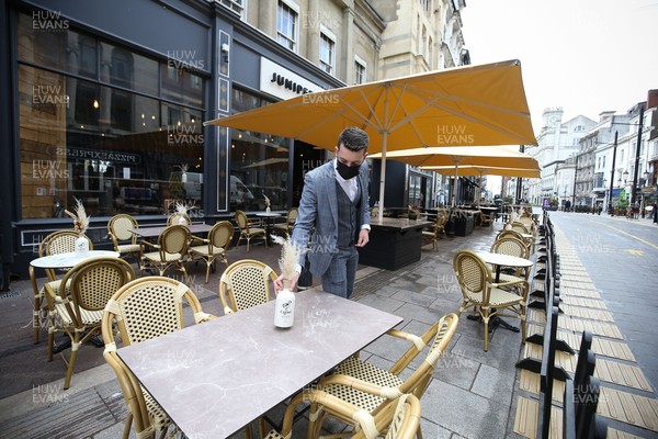 260421 Bars and restaurants reopen, Wales - Staff at Juniper Place in Cardiff prepare to open as bars and restaurants in Wales are allowed to serve customers outdoors after a lifting of Welsh Government COVID-19 restrictions today