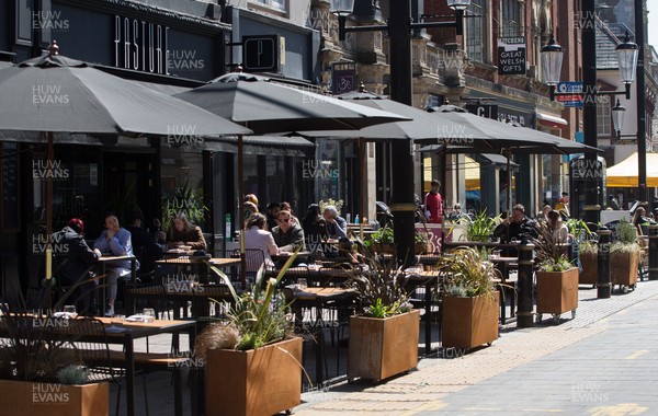 260421 Bars and restaurants reopen, Wales - Staff at bars and restaurants in Cardiff welcome customers back as they are allowed to serve customers outdoors after a lifting of Welsh Government COVID-19 restrictions today