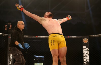 081218 - Cage Warriors 100 - Nicolas Dalby (Yellow shorts) celebrates winning over Philip Mulpeter (blue shorts) 