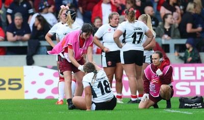 300825 - Canada v Wales, Women’s Rugby World Cup - Jenni Scoble of Wales receives treatment from Dr Gwennan Williams, Wales Women team doctor, and Cara Jones, physio before leaving the pitch with an injury