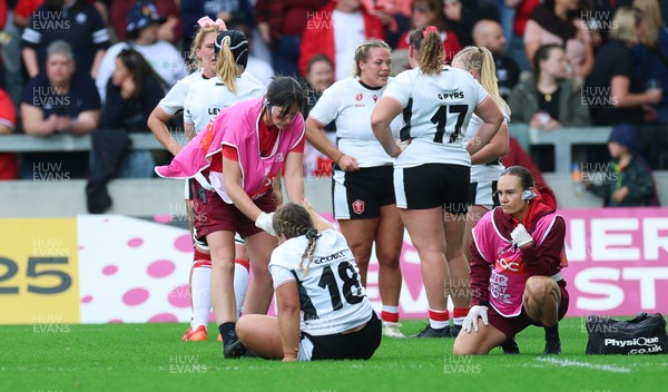 300825 - Canada v Wales, Women’s Rugby World Cup - Jenni Scoble of Wales receives treatment from Dr Gwennan Williams, Wales Women team doctor, and Cara Jones, physio before leaving the pitch with an injury