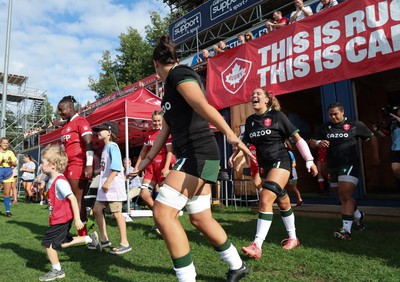 270822 - Canada Women v Wales Women, Summer 15’s World Cup Warm up match - Georgia Evans of Wales laughs as Sioned Harries of Wales is left behind by her mascot as he runs onto the pitch while she walks out for the start of the match