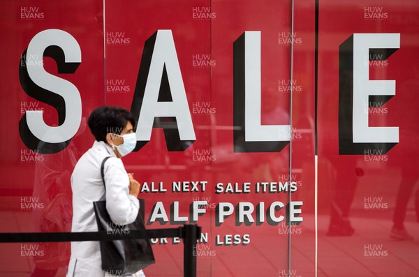 150720 - Picture shows a women wearing a mask walking past a sale sign in the window of Next in Cardiff, South Wales during the coronavirus pandemic