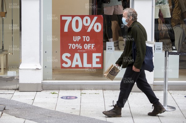 150720 - Picture shows a man wearing a face mask walking past a sale sign in Cardiff, South Wales during the coronavirus pandemic