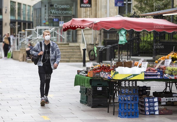 150720 - Picture shows a man wearing a face mask walking past a fruit and vegetable stall in Cardiff, South Wales during the coronavirus pandemic