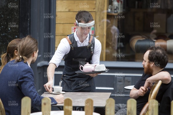 150720 - Picture shows a waiter serving tea whilst wearing a PPE face shield in Cardiff, South Wales during the coronavirus pandemic