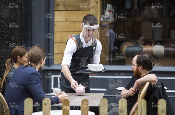 150720 - Picture shows a waiter serving tea whilst wearing a PPE face shield in Cardiff, South Wales during the coronavirus pandemic