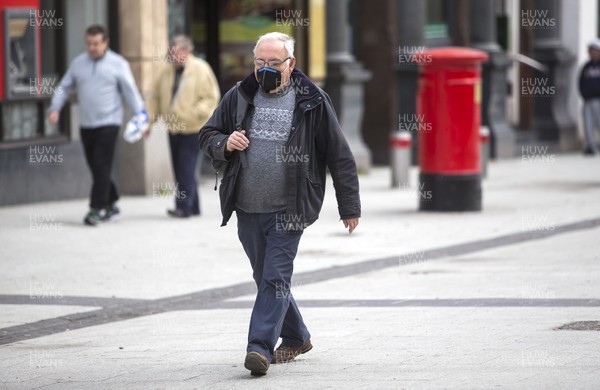 300320 - Cardiff City Centre Lockdown - A man walks along Queens Street wearing a mask