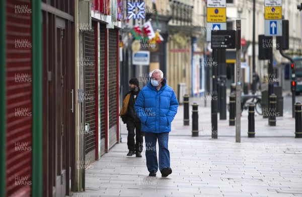 300320 - Cardiff City Centre Lockdown - A man wearing a mask walks along Castle Street