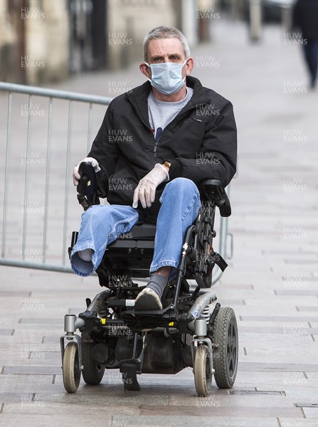 300320 - Cardiff City Centre Lockdown - A man in his wheelchair goes down St Mary Street, Cardiff during the coronavirus lockdown