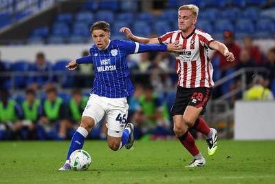 260825 - Cardiff City v Cheltenham Town - Carabao Cup Round Two - Cian Ashford of Cardiff City is challenged by Tommy Backwell of Cheltenham Town