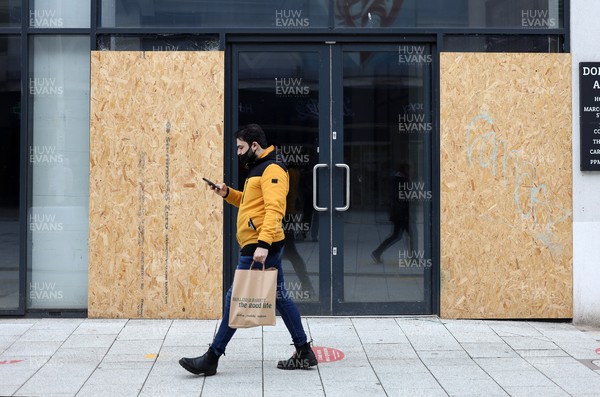 040321 - Picture shows a man walking past an empty shop on Queens Street, Cardiff today as the current coronavirus restrictions are set to stay in place