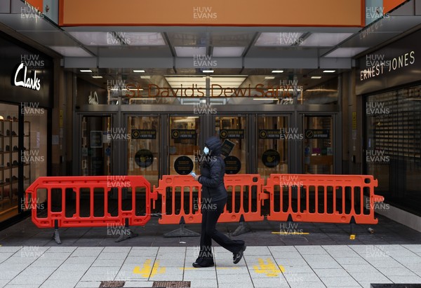 040321 - Picture shows a woman walking past a closed St Davids shopping centre on Queens Street, Cardiff today as the current coronavirus restrictions are set to stay in place