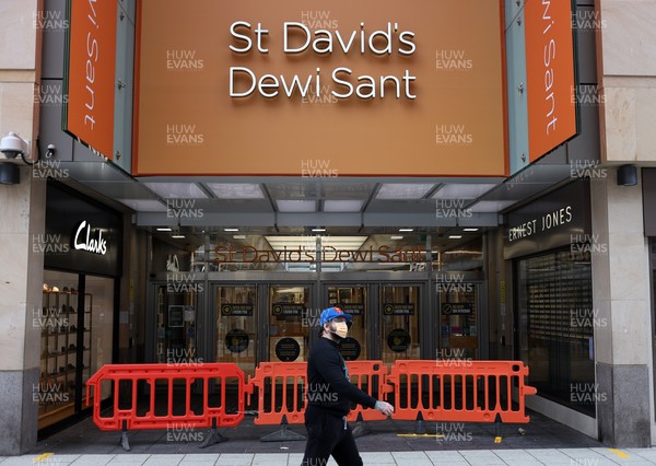 040321 - Picture shows a man walking past a closed St Davids shopping centre on Queens Street, Cardiff today as the current coronavirus restrictions are set to stay in place