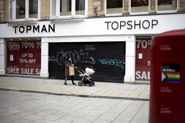 040321 - Picture shows a woman walking past a closed Topman and Topshop on Queens Street, Cardiff today as the current coronavirus restrictions are set to stay in place