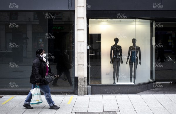 040321 - Picture shows a woman walking past a closed down shop on Queens Street, Cardiff today as the current coronavirus restrictions are set to stay in place