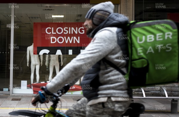 040321 - Picture shows an Uber Eats rider going past a closed down shop on The Hayes, Cardiff today as the current coronavirus restrictions are set to stay in place