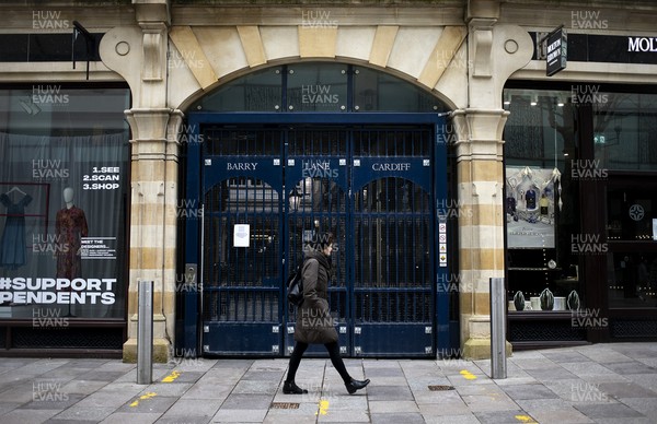 040321 - Picture shows a woman walking past a closed shopping arcade on The Hayes, Cardiff today as the current coronavirus restrictions are set to stay in place