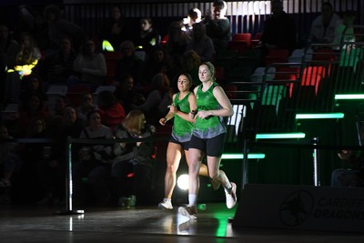 220225 - Cardiff Dragons v Birmingham Panthers - Netball Super League - Elle McDonald and Bethan Dyke of Cardiff Dragons runs out for the start of the match