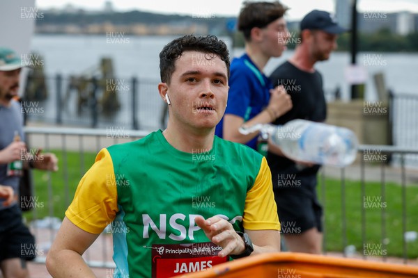 011023 - Principality Building Society Cardiff Half Marathon 2023 - Cardiff Bay - Runners throwing water bottles into recycling bins