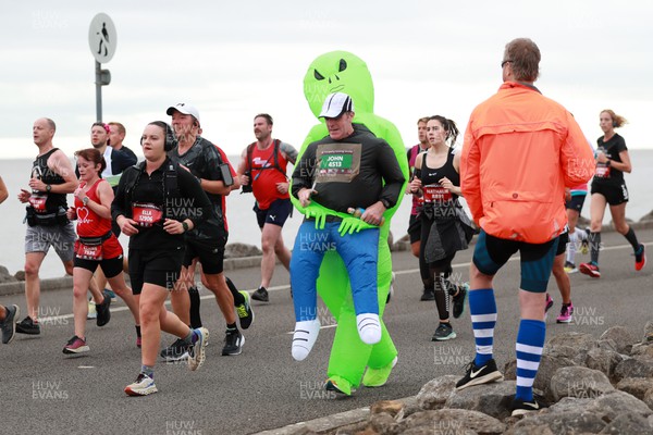 011023 - Principality Building Society Cardiff Half Marathon 2023 - Runner dresses as alien carrying man at the Cardiff Barrage