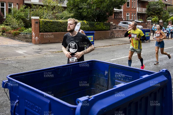 011023 - Principality Building Society Cardiff Half Marathon 2023 - Roath Park and Lake - Runners throwing water bottles into recycling bins