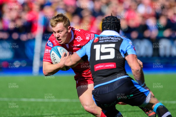 090422 - Cardiff Rugby v Scarlets - United Rugby Championship - Sam Costelow of Scarlets is tackled by Matthew Morgan of Cardiff Rugby