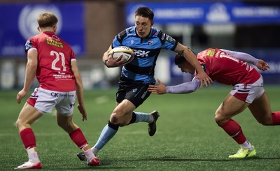 191225 - Cardiff Rugby v Scarlets, United Rugby Championship - Josh Adams of Cardiff Rugby takes on Joe Hawkins of Scarlets and Archie Hughes of Scarlets