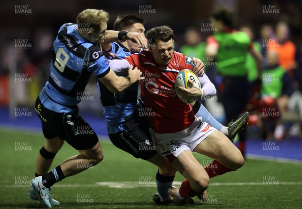 191225 - Cardiff Rugby v Scarlets - United Rugby Championship - Tom Rogers of Scarlets is tackled by Aled Davies and Josh Adams of Cardiff 