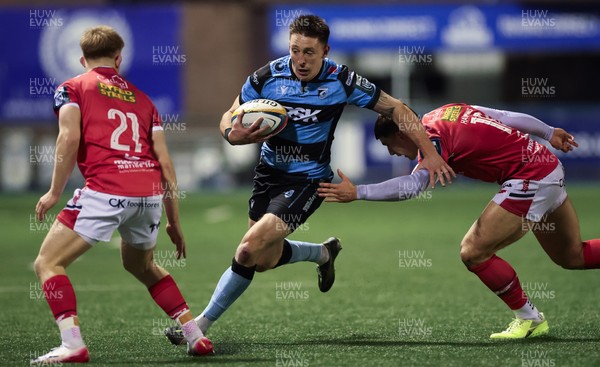 191225 - Cardiff Rugby v Scarlets, United Rugby Championship - Josh Adams of Cardiff Rugby takes on Joe Hawkins of Scarlets and Archie Hughes of Scarlets