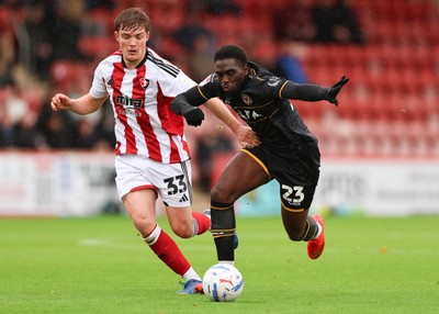 241026 Cheltenham Town v Newport County, EFL Sky Bet League 2 -  Michael Adu-Poku of Newport County gets between Freddy Willcox of Cheltenham Town and Ben Stevenson of Cheltenham Town