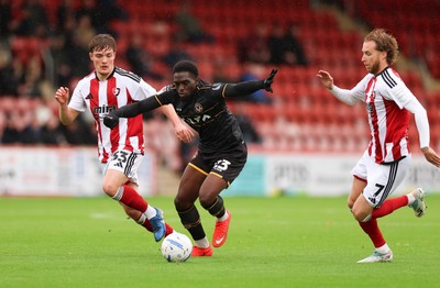 241026 Cheltenham Town v Newport County, EFL Sky Bet League 2 -  Michael Adu-Poku of Newport County gets between Freddy Willcox of Cheltenham Town and Ben Stevenson of Cheltenham Town