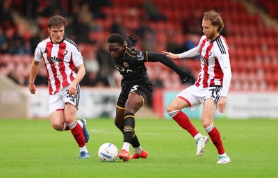 241026 Cheltenham Town v Newport County, EFL Sky Bet League 2 -  Michael Adu-Poku of Newport County gets between Freddy Willcox of Cheltenham Town and Ben Stevenson of Cheltenham Town