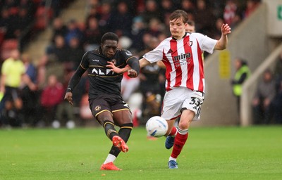 241026 Cheltenham Town v Newport County, EFL Sky Bet League 2 - Michael Adu-Poku of Newport County shoots at goal as Freddy Willcox of Cheltenham Town closes in