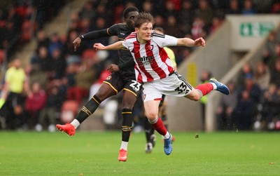 241026 Cheltenham Town v Newport County, EFL Sky Bet League 2 - Michael Adu-Poku of Newport County shoots at goal as Freddy Willcox of Cheltenham Town closes in