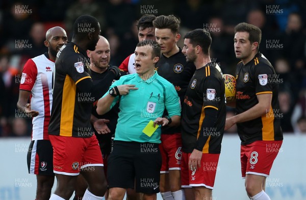 301217 - Cheltenham Town v Newport County - SkyBet League Two - Newport players gather round referee Antony Coggins as Nigel Atangana of Cheltenham Town is given a yellow card