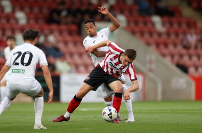 230725 - Cheltenham Town v Swansea City - Pre Season Friendly - Freddy Willcox of Cheltenham Town is tackled by Ronald of Swansea City 