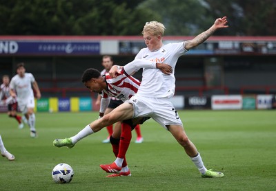 230725 - Cheltenham Town v Swansea City - Pre Season Friendly - Melker Widell of Swansea City is challenged by Harrison Sohna of Cheltenham Town 