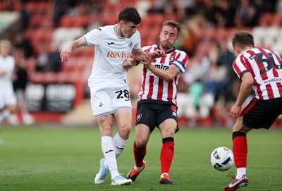 230725 - Cheltenham Town v Swansea City - Pre Season Friendly - Joel Cotterill of Swansea City is tackled by Luke Young of Cheltenham Town 