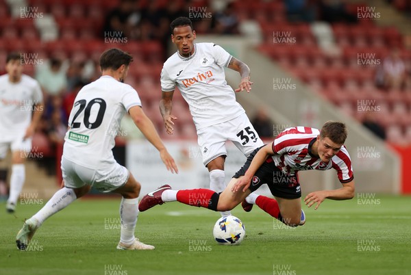 230725 - Cheltenham Town v Swansea City - Pre Season Friendly - Freddy Willcox of Cheltenham Town is tackled by Ronald of Swansea City 