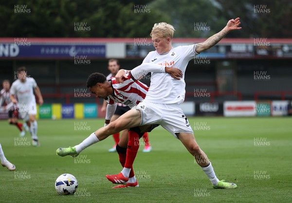 230725 - Cheltenham Town v Swansea City - Pre Season Friendly - Melker Widell of Swansea City is challenged by Harrison Sohna of Cheltenham Town 