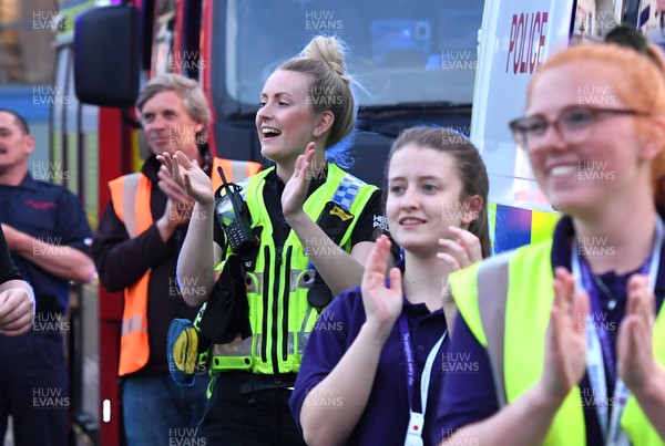 230420 - Clap for Carers - A police officer outside temporary field hospital Dragon's Heart Hospital at Principality Stadium taking part in Thursday evenings "Clap for Carers" at 8pm