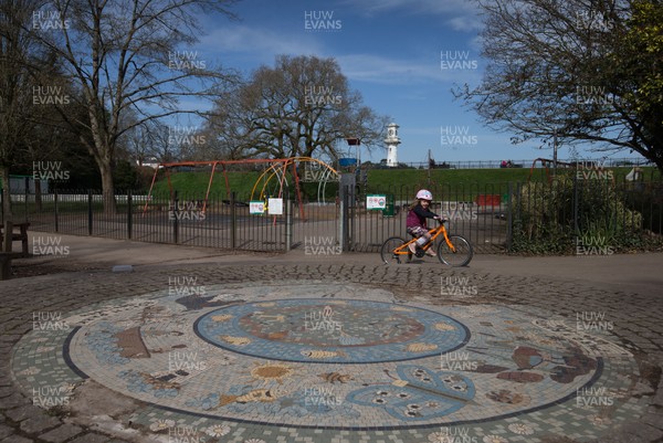 230320 - A child cycles past the deserted children's play area at Roath Park in Cardiff, after the council closed all children's play area at the city's parks