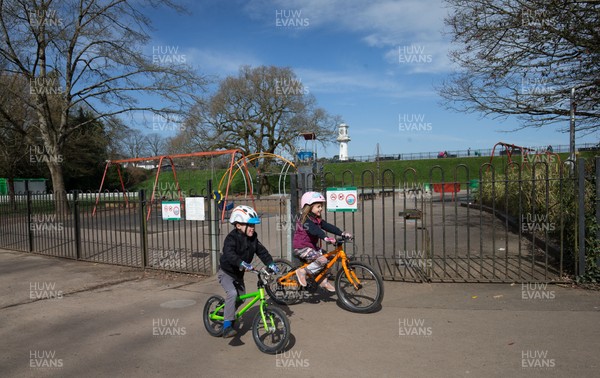 230320 - Children cycle past the deserted children's play area at Roath Park in Cardiff, after the council closed all children's play area at the city's parks