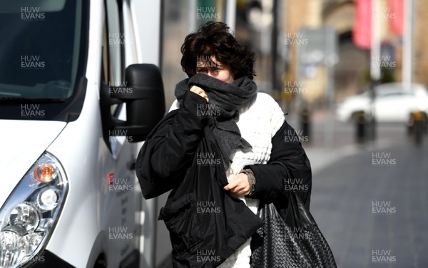 230320 - Coronavirus Outbreak - A lady covers her mouth as she walks through streets in Cardiff City centre during Monday morning
