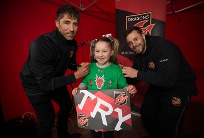 200218 - Dragons players Gavin Henson and Dorian Jones as they sign a tee shirt for Adie Moore, 8, from Ebbw Vale as they meet fans at Festival Park, Ebbw Vale